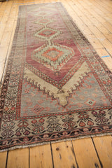 Worn fringe with aubergine and green floral motifs on the Oushak rug border.