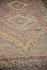 Distressed Oushak rug detail with serrated motifs, faded aubergine, saffron, and wear.