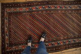 Kurdish rug field with diagonal rows of repeating brick red, navy, and ivory blossoms.