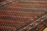 Vintage Kurdish rug detail: repeating blossoms, geometric border in chocolate, navy, brick red, even wear.