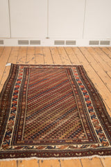 Vintage Kurdish rug corner, showing diagonal blossoms and intricate geometric border in brick red.