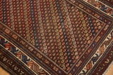 Corner of vintage Kurdish rug, geometric blue, red, ivory borders, repeating blossoms, and wear.
