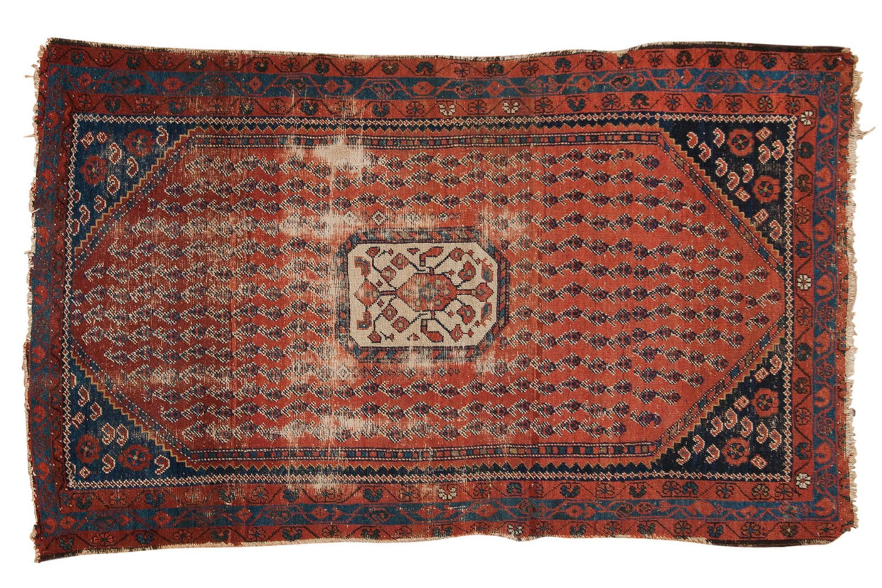 Antique Kurdish Hamadan rug with worn madder red boteh field, ivory medallion, navy blue borders.