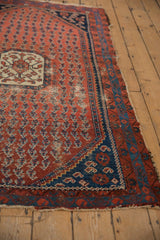 Antique Kurdish Hamadan rug corner: navy spandrel, floral boteh designs, and tattered ends.