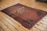 Kurdish Hamadan rug detail: navy corner spandrel, floral botehs, madder red field, worn fringe.
