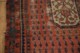 Antique Kurdish Hamadan rug with madder red field, navy botehs, floral spandrel, and worn tattered side.