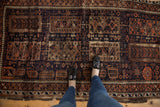 Antique Belouch rug detail: navy, madder red geometric medallions, botehs, and visible material loss.