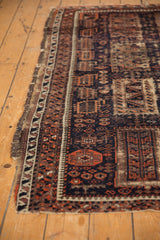 Antique Belouch fragment with tattered perimeter and geometric navy, madder red, ivory patterns.