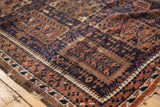Antique Belouch rug: worn edge, hand-knotted geometric motifs in navy, madder red, and ivory.