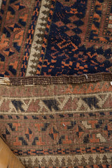 Hand-knotted back of an Antique Belouch rug, showcasing tattered brown selvage and geometric pile.