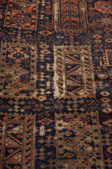 Geometric navy, madder red patterns on antique Belouch fragment, with visible material reduction.