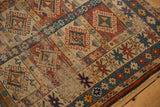 Antique Caucasian rug's paneled geometric medallions, brick red, sky blue, and exposed foundation.