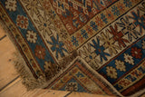 Exposed foundation, tattered fringe, and geometric hook-and-latch motifs on the Antique Caucasian rug.
