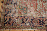 Worn pile of an antique Heriz rug corner, showcasing navy, cherry, and green floral motifs.
