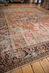 Antique Heriz rug's geometric border in cherry red, navy, and mallard green, showing wear.