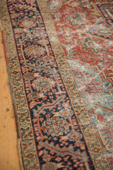 Antique Heriz carpet's navy borders, rectilinear vinery, visible wear, and polychrome selvage.