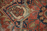 Antique Heriz rug: intricate geometric pattern, cherry red, navy, mallard green, aged pile texture.