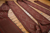Geometric diamond pattern on several unrolled antique Verneh rug sections in brick red.