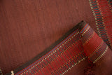 Textural detail of antique Verneh rug's brick red flat weave and banded edge in red, blue, green.
