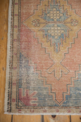 Distressed vintage Oushak rug edge with fringe, showing worn pale terra cotta geometric pattern.