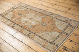 Distressed Oushak runner corner with worn pale chestnut, ivory, and charcoal patterns.