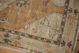 Distressed vintage Oushak rug corner, dusty copper, antique ivory, charcoal tones, visible wear.