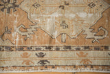 Distressed Oushak rug runner's worn pile, revealing pale copper and ivory geometric motifs.