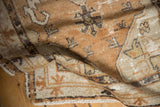 Distressed Oushak rug pile, folded, with copper, ivory geometric design and fringe.