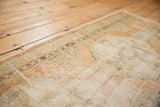 Corner of a distressed vintage Oushak rug runner, revealing even wear and faded pale orange patterns.