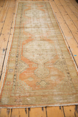 Distressed texture and secured side of vintage Oushak runner in muted orange and earth tones.