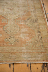 Textured surface of a distressed Oushak rug with faded terra cotta and sand tones.
