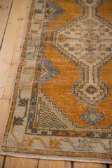 Distressed Oushak rug border showing pale seafoam germinating plant motif and saffron orange field.