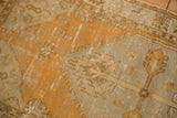 Distressed texture of a vintage Oushak rug with geometric patterns in dusty tangerine and ivory.
