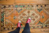 Distressed Oushak runner with tangerine medallion, ivory field, and turquoise vine border.