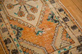 Distressed tangerine orange Oushak medallion, revealing worn knot heads and charcoal hook motifs.