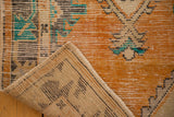 Close-up of distressed tangerine orange Oushak rug pile revealing its hand-knotted foundation.