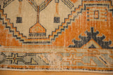 Distressed Oushak runner detail: geometric tangerine, seafoam, slate blue pattern with visible wear.