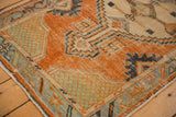 Distressed vintage Oushak rug corner with seafoam grid spandrel and tangerine field.