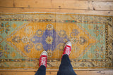 Distressed Oushak runner corner, saffron yellow and mint green, with foundation visible.