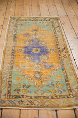 Distressed Oushak rug, showing royal blue medallion, wear, and visible foundation.