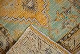 Folded Oushak rug corner showing distressed saffron yellow pile and visible foundation weave.