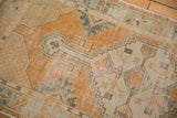 Distressed tangerine orange and ivory vinery on a vintage Oushak rug corner.