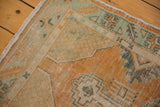 Distressed vintage Oushak runner corner with pale tangerine, mint geometric patterns, and original selvage.