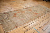 Distressed Oushak runner end: truncated border, foundation wear, faded blush and ivory floral motifs.