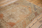 Distressed vintage Oushak runner's secured end, with truncated borders and worn pile.
