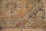 Distressed Oushak rug corner showing its barber pole border and textural wear in terracotta and ivory.