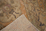 Distressed Oushak rug pile with visible hand-knotted foundation, displaying muted beige, blush, and rust tones.
