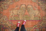 Close-up of distressed lion pictorial and worn knot heads on a vintage Oushak rug.