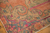 Distressed Oushak rug corner with even wear showing faint foundation, secured edge.