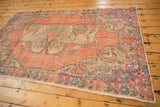 Distressed vintage Oushak rug corner, showing fringe and a pictorial lion motif.